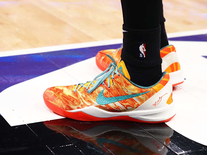 View of orange and green Nike Kobe shoes.
